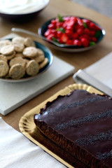 Various food served on a table: Chocolate poppy seed cake, strawberries, whipped cream and crackers. Selective focus.