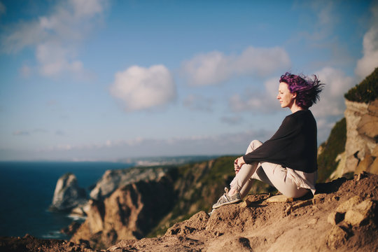 Female sitting on the cliff watching beautiful ocean view