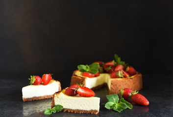 Slice of cheesecake with strawberries and mint on a dark background. Cheesecake New York. Advertising. Restaurant menu.
