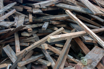 Wooden boards thrown into a chaotic pile. A pile of building material after the breaking of a wooden house. Wooden construction debris lies in a heap.