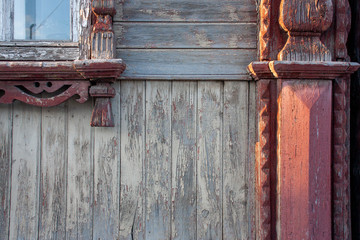 The vintage carved platbands on the wooden wall of an old house.  Red the pattern on the wooden wall, closeup.