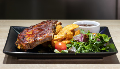 Baked pork ribs with barbecue or BBQ sauce and wedges