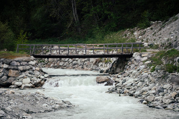 Waterfall, river and bridge in the alpine mountains.