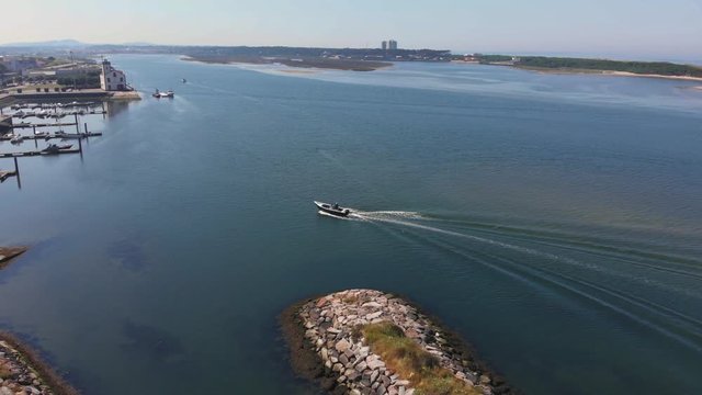 DRONE AERIAL FOOTAGE - A boat arrives in Marina Esposende with beautiful view on Esposende, Portugal. The jetty structure that protects the coastline from the currents and tides.