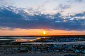 Beautiful sunset over Pagham Nature Reserve with the sun sinking towards the horizon and the colours reflecting off the lake. Aerial view.