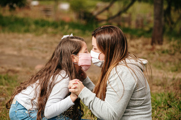 Portrait of young mother with young daughter using mask. Mother and daughter wearing mask to protect Covid-19, quarantine. Kiss. Stay at home concept.