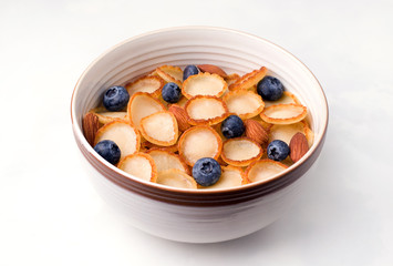 Healthy breakfast of tiny pancake cereal with berries and nuts on a white background