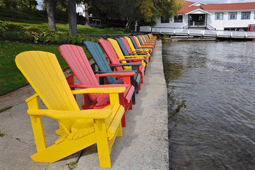 Diminishing perspective view of multi-colored Muskoka Chairs in the lakefront of the tourist resort