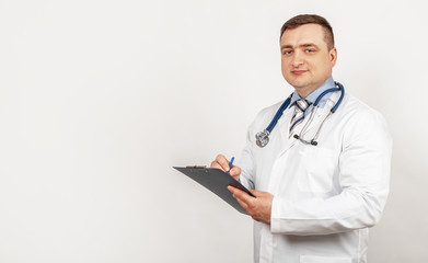 Men doctor writes with a pen a document on a tablet, writes a medical history.