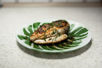 fried chicken in a green white plate with a crispy golden crust and greens dill and parsley