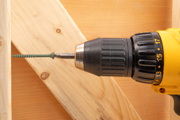 closeup of a yellow battery operated drill with screwdriver bit in a residential frame construction setting