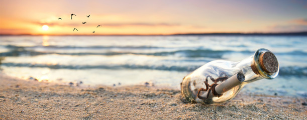 Flaschenpost lieht im Sand am Strand