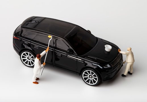 Miniature people cleaning automobile at car wash
