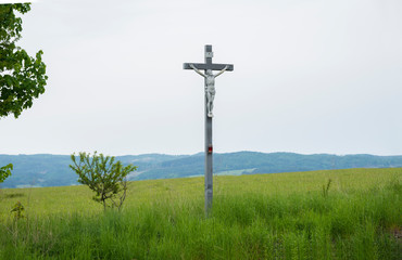 Fototapeta na wymiar Crucifix in the green field. Christianity symbol.