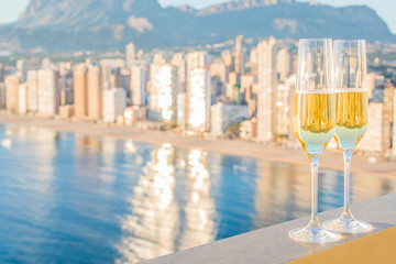 Two glass of champagne against Levante Beach, Benidorm, Valencia, Spain
