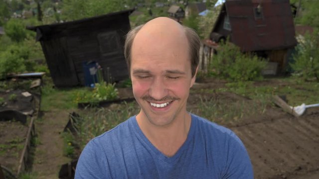 portrait, balding young man in the countryside looking at the camera, smiling