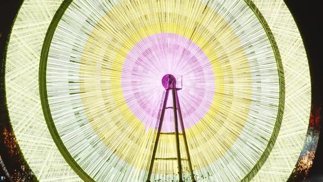 The time-laps of the Ferris wheel rotates and leaves behind a luminous trace from the colored lights.