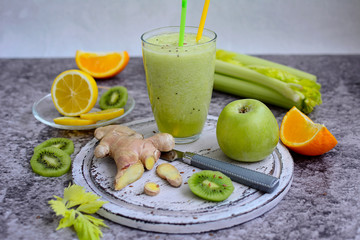 Nutritious smoothie of celery, lemon, kiwi and ginger on a gray background. Vegetarianism concept