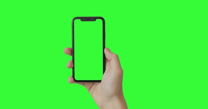 Man hand holding the smartphone on green screen chroma key background.  Mobile phone mock-up for your product. The iPhone Xr model in vertical orientation portrait mode.