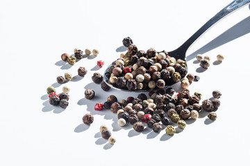 mix of allspice in a metal spoon. isolated on white