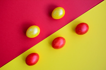 Top view of red and yellow easter eggs diagonally on a red-yellow background.