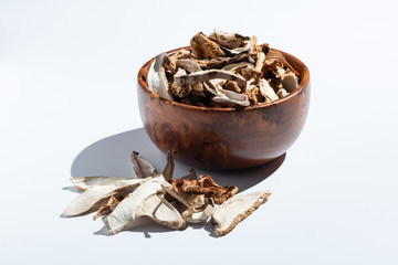 dried mushrooms in a wooden bowl isolated on white