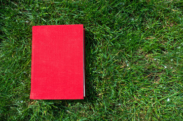 Red book on the green lawn grass outside