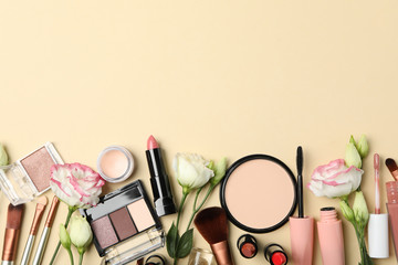 Fototapeta premium Different makeup cosmetics and flowers on beige background. Female accessories