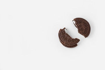 Broken into two parts chocolate cookies with milk filling. Cookies are isolated on a white background