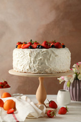 Composition with delicious berry cream cake on white wooden table. Tasty dessert