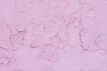 A wall painted in old cracked pink paint. The photo was taken close-up for your grunge design.