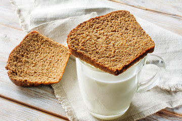 A glass of fermented baked milk and slices black bread on a wooden rustic table. Traditional breakfast.