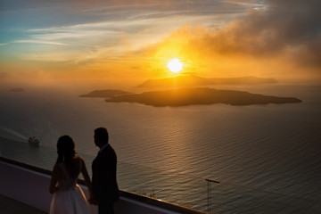 Fototapeta na wymiar Silhouette of a loving couple on the background of the setting sun, mountains, islands and sea. Santorini. Greece. Just married. Walk.