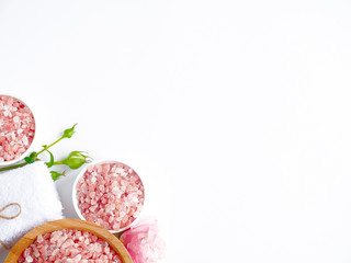 Spa flatlay composition. Sea salt in wooden jar, towel, flower on white background. Top view, copyspace. Daily care concept, relax and rest, bath procedure