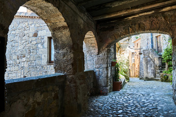 Cobblestone street with stone arcades in the city of Sorano in Tuscany, Italy.