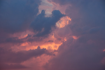 Fire-red light from the sun breaks through dark blue clouds