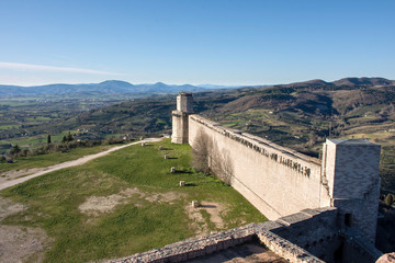 Fototapeta na wymiar Paredón de castillo medieval en colinas con día soleado y cielo azul 