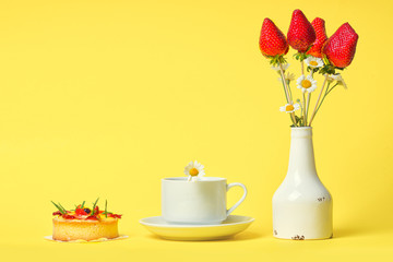 Berry bouquet. A bouquet of strawberries in a white small vase and a cup of tea and cake on a yellow background.
