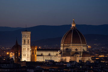 Catedral de Florencia iluminada a la noche con colinas de fondo