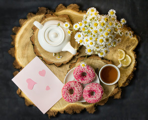 Breakfast. Surprise.Cup of tea with chamomile and delicious donuts.Beautiful bouquet of field daisies.