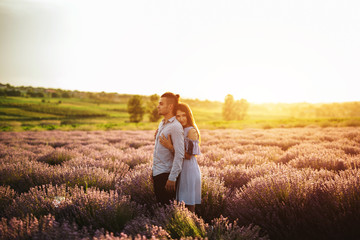 Naklejka na ściany i meble Beautiful young couple dating and walking together outdoor in lavender field.