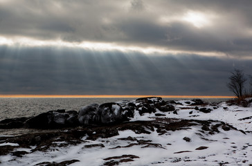 The sun breaking through storm clouds over Lake Superior in Minnesota on a cold winter day.