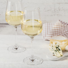 Two glasses of white wine served with cheese board on white background. Wine mood concept
