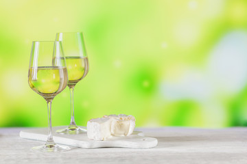 White wine served with cheese plate on light green background. Two wineglasses of vino verde. Seasonal holidays concept