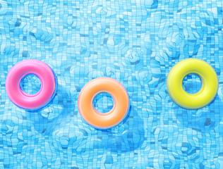 Group of Pool floats, ring floating in a refreshing blue swimming pool with palm tree leaf shadows in water
