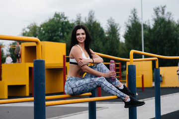 Sexy girl does sports and drinks water in the open air. Fitness. Healthy lifestyle