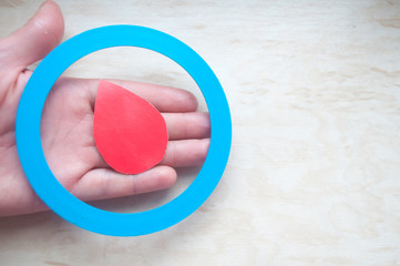 Diabetes awareness. World Diabetes Day. Hand holds a blue circle and a drop blood. Symbol diabetes. Insulin dependence. 