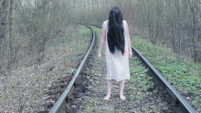 ghost of woman stands in forest on railway track.
