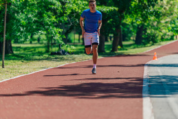 Handsome man jogging during sunny morning out on the race track