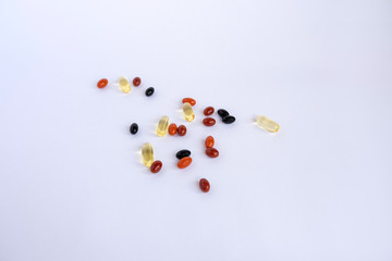 Mix of colorful vitamins and omega-3 fish oil in the form of capsules on a white background.